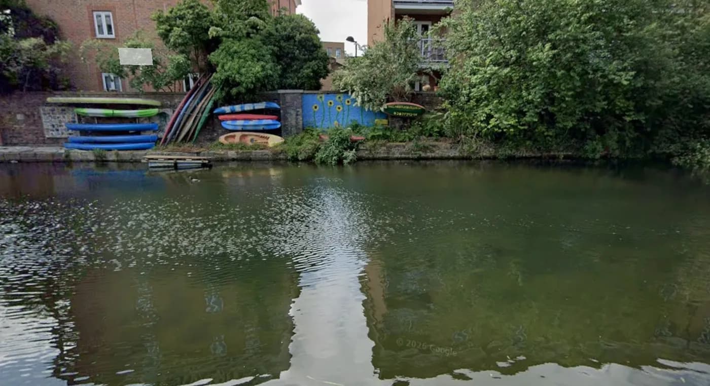 Street View of the canal bank behind the flats, with kayaks stacked against the wall